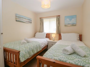 A bedroom with two single beds and a nightstand at 14 The Dell Mundesley