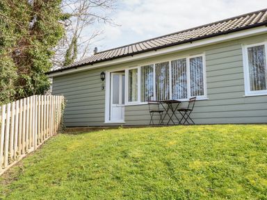 Exterior of a single-story house with a small table and two chairs on the grass at 15 The Dell in Mundesley