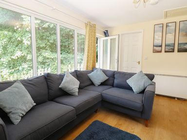 A living room with a sofa and door at 15 The Dell Mundesley