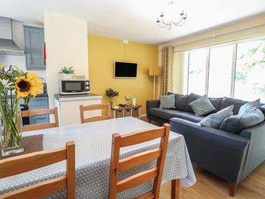 A living room with a dining table and sofa at 15 The Dell Mundesley