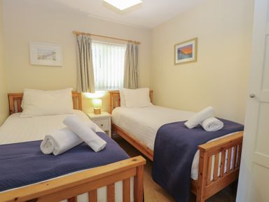 A bedroom with two single beds and a nightstand at 15 The Dell Mundesley