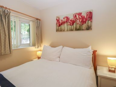 A bedroom with a bed and flowers on the wall at 15 The Dell Mundesley