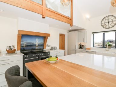 A kitchen with a stove under a wooden hood and a bowl of fruit on a wooden countertop at Bilsham Meadows in Aust