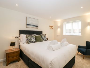 A bedroom with a double bed bedside table with lamp wall art window and armchair at Bilsham Meadows in Aust