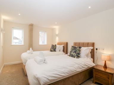A bedroom with two single beds pillows and towels on each bed bedside table and lamp at Bilsham Meadows in Aust