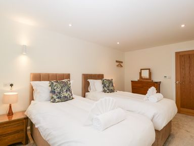 A bedroom with two single beds with white bedding and patterned pillows at Bilsham Meadows in Aust