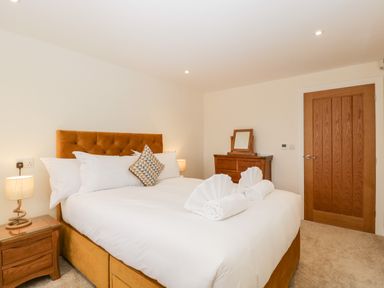 A bedroom with a bed a wooden dresser and a wooden door at Bilsham Meadows in Aust