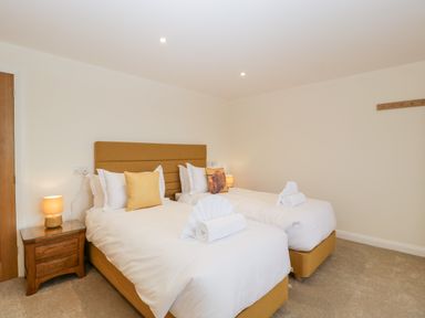A bedroom with two single beds with yellow headboards and white bedding at Bilsham Meadows in Aust