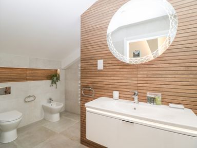 A bathroom with a toilet bidet sink and round mirror at Bilsham Meadows in Aust