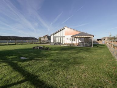 A house with a patio and covered hot tub in a fenced grassy yard at Bilsham Meadows in Aust