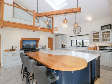 A kitchen with an island and bar stools at Bilsham Meadows in Aust