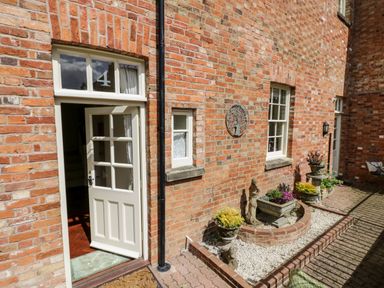 An open white door on a brick wall with the number 4 above it and a garden area with plants at 4 The Old Council House in Shipston-On-Stour