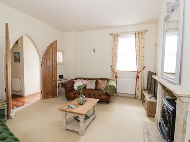 A living room with a brown leather sofa a wooden coffee table a fireplace and a wooden TV stand at 4 The Old Council House Shipston-On-Stour