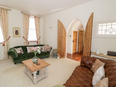 A living room with green and brown sofas and a wooden coffee table at 4 The Old Council House in Shipston-On-Stour