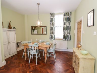 A dining room with wooden floor a wooden table surrounded by four chairs and a window with curtains at 4 The Old Council House Shipston-On-Stour