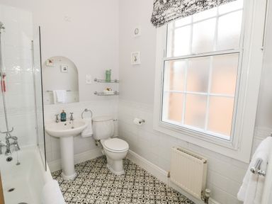 A bathroom with a bathtub shower sink toilet window and tiled floor at 4 The Old Council House in Shipston-On-Stour