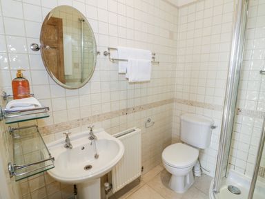 A bathroom with a sink mirror towel rack toilet and shower at 4 The Old Council House Shipston-On-Stour