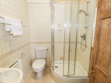 A bathroom with a toilet sink towel rack and curved glass shower enclosure at 4 The Old Council House in Shipston-On-Stour