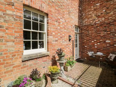A brick courtyard with potted plants a small table and two chairs at 4 The Old Council House Shipston-On-Stour