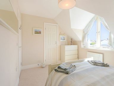 A bedroom with a bed with folded towels a chest of drawers and a window with curtains at Smugglers Cove 7 in Beadnell