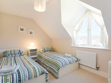 A bedroom with two single beds striped bedding and a window at Smugglers Cove 7 in Beadnell