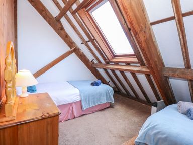 A bedroom with two single beds and a wooden dresser under a skylight at Timbers in Weybourne