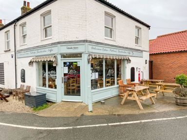 A corner cafe with outdoor wooden tables and chairs at Timbers in Weybourne