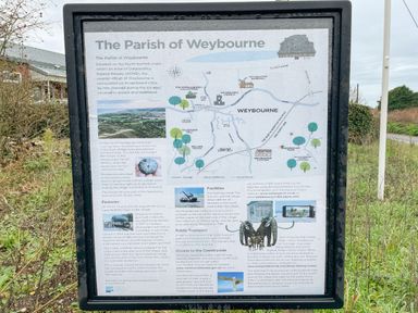 An outdoor information board about the parish of Weybourne with maps images and text
