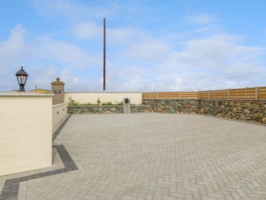 An outdoor paved area with a stone wall and wooden fence at Refail Fach Near Cemaes Bay