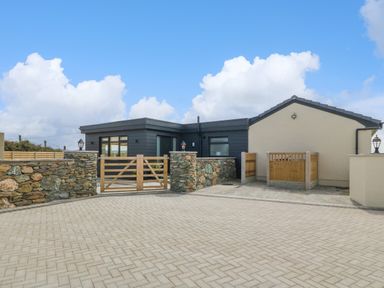 An exterior view of a house with stone walls and wooden gates at Refail Fach Near Cemaes Bay
