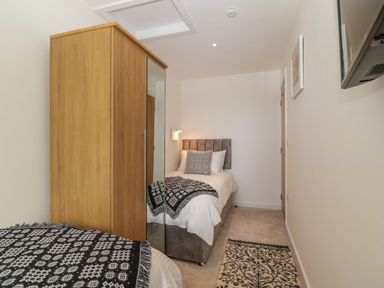 A bedroom with two single beds a wooden wardrobe a small rug and a wall-mounted television at Refail Fach Near Cemaes Bay