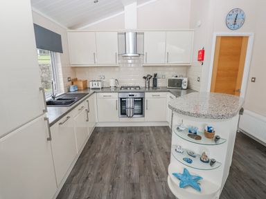 A kitchen with a sink, oven, and countertop at Dono's Lodge, Stepaside near Kilgetty, Heritage Park