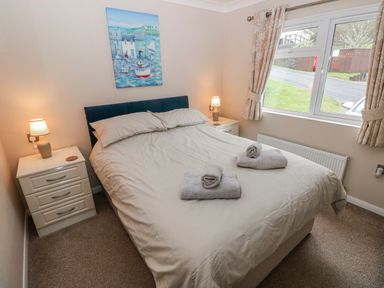 A bedroom with a bed and bedside tables at Dono's Lodge, Stepaside near Kilgetty, Heritage Park