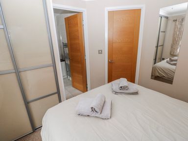 A bedroom with a bed and towels on blankets at Dono's Lodge, Stepaside near Kilgetty, Heritage Park