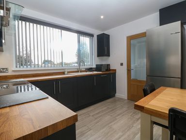 A kitchen with wooden countertops a stainless steel refrigerator a wooden door and a table with chairs at Ty Nain in Llanfairpwllgwyngyll