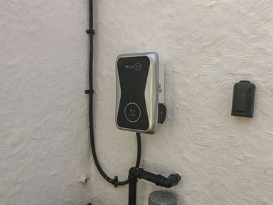 An electric vehicle charging station mounted on a textured wall at Ty Nain in Llanfairpwllgwyngyll
