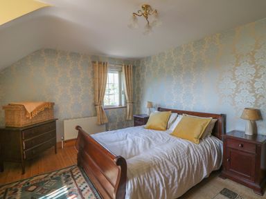 A bedroom with a wooden bed and bedside tables at Bolger House Ballintubbrid near Kilmuckridge County Wexford