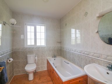 A bathroom with a bathtub toilet sink and round mirror at Bolger House in Ballintubbrid near Kilmuckridge County Wexford