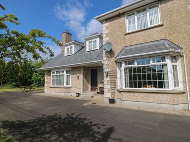 The exterior of a two-story house with a driveway and garden area at Bolger House in Ballintubbrid near Kilmuckridge County Wexford