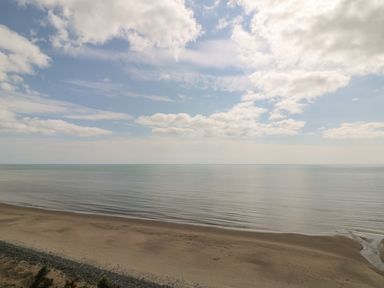 A sandy beach with calm sea under a partly cloudy sky at Bolger House in Ballintubbrid near Kilmuckridge County Wexford