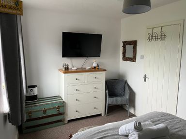 A bedroom with a television, dresser, and armchair at 22 Longstone Park Beadnell
