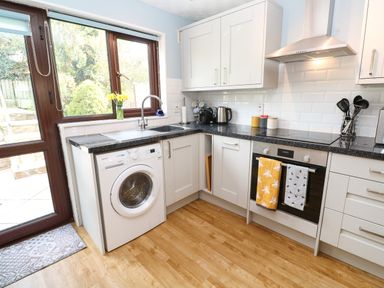 A kitchen with washing machine stove sink kettle and utensils at Bumbles in Padstow