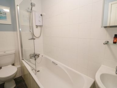 A bathroom with a bathtub shower toilet and sink at Bumbles in Padstow