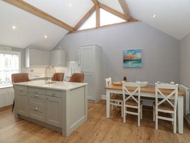 A kitchen with an island and three chairs and a dining table with four chairs at Belle View in Llaniestyn near Abersoch
