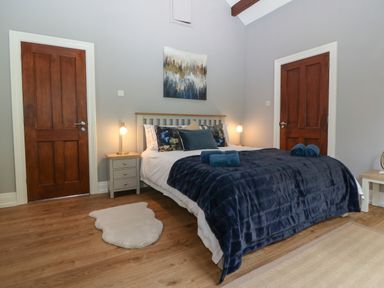 A bedroom with a bed covered in blue bedding between two wooden doors at Belle View in Llaniestyn near Abersoch