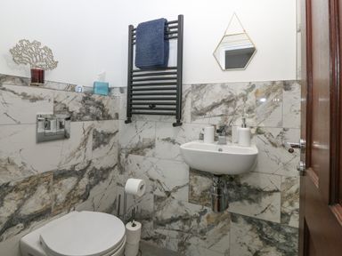 A bathroom with a toilet sink towel rack and a small mirror at Belle View in Llaniestyn near Abersoch