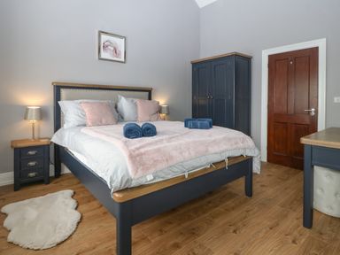 A bedroom with a bed pillows and rolled towels bedside table wardrobe and a door at Belle View in Llaniestyn near Abersoch