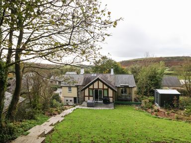 A backyard with a lawn shed and stone steps leading to a house with a patio in a rural area at Belle View in Llaniestyn near Abersoch