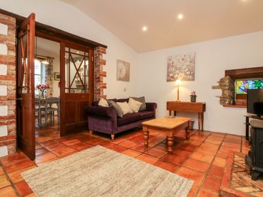 A living room with a purple sofa wooden coffee table and stained glass window at The Shippen in Gooseham near Kilkhampton