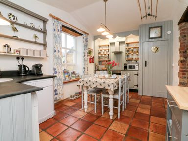 A kitchen with dining table and chairs stove microwave dishwasher and shelves at The Shippen in Gooseham near Kilkhampton